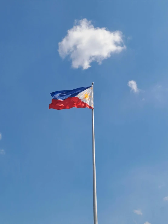 flag on pole with white clouds on blue sky in background