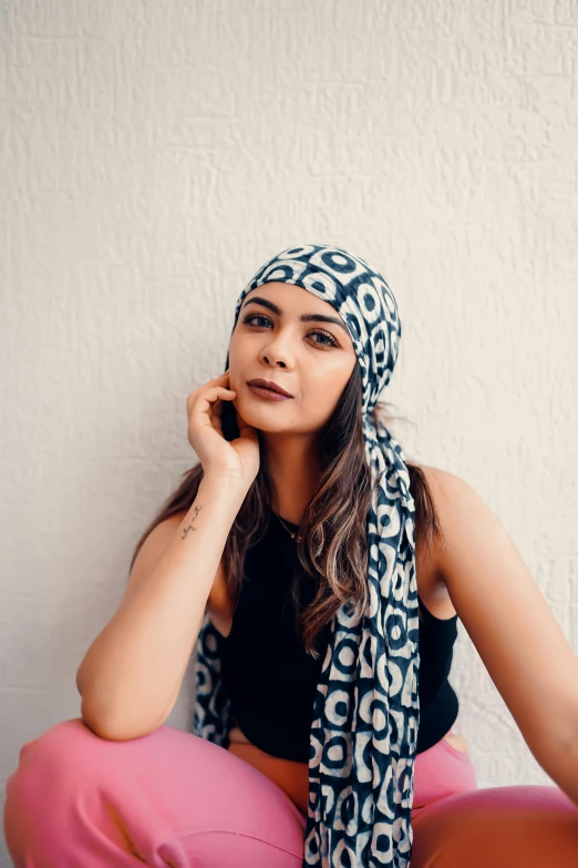 a woman sits with a patterned head scarf and talks on the phone