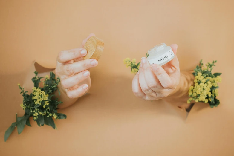 two hands holding a wedding ring next to a flower