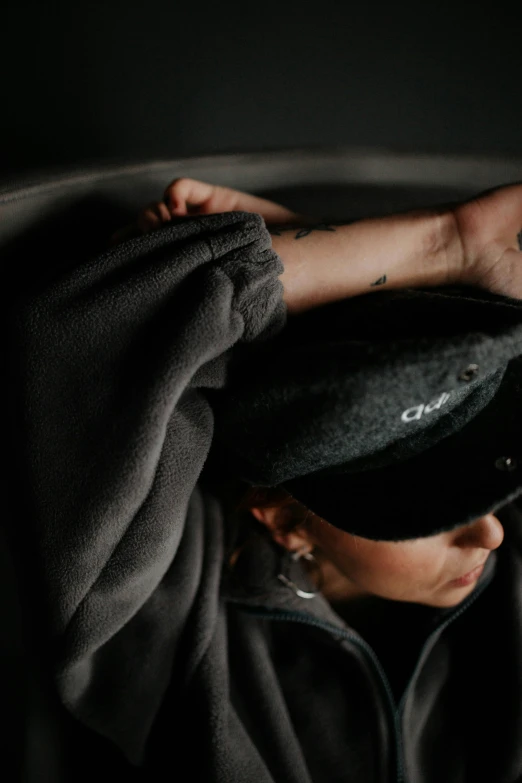 a person holding on to a black hat while sitting down