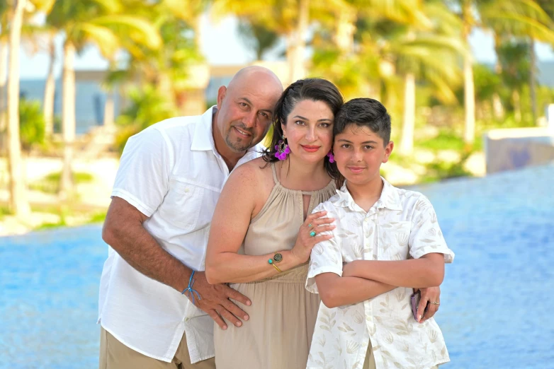 a man and two children posing for a po with palm trees in the background