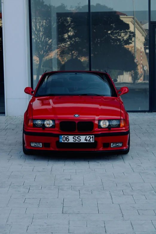 the front end of a red sports car parked near a building