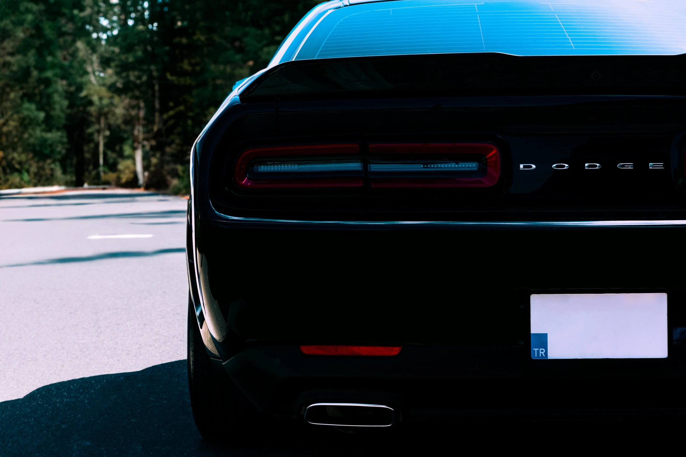 the tail end of a black sports car parked on a road