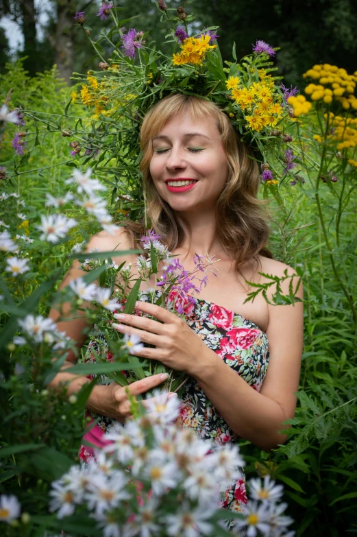 woman with floral crown standing amongst field of flowers