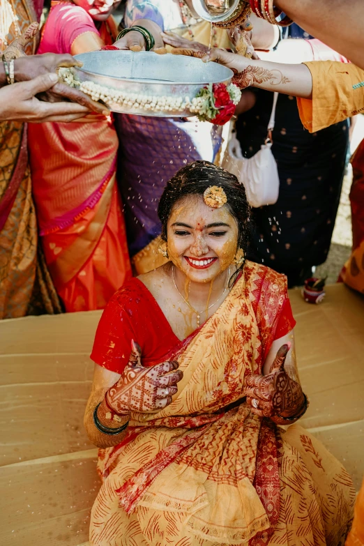 a woman in traditional garbabe is sitting down while having her face painted