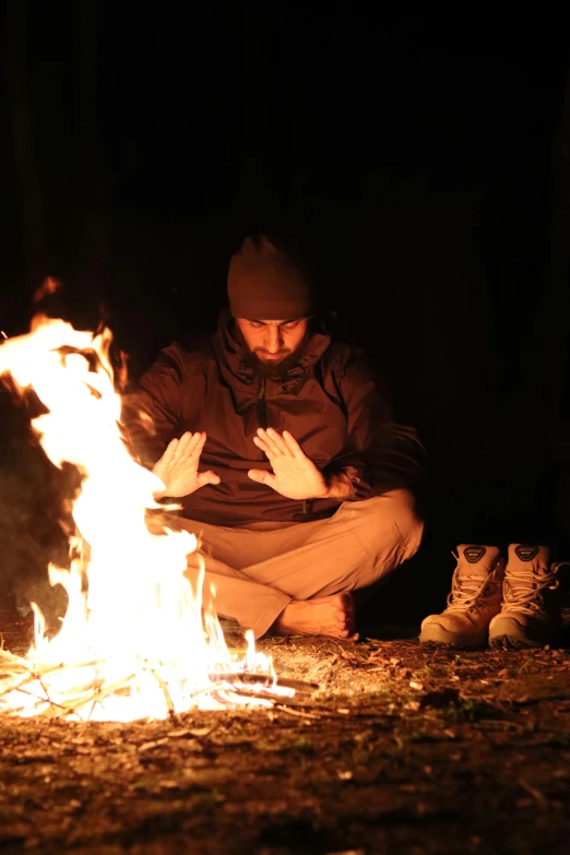 a person kneeling down next to a fire