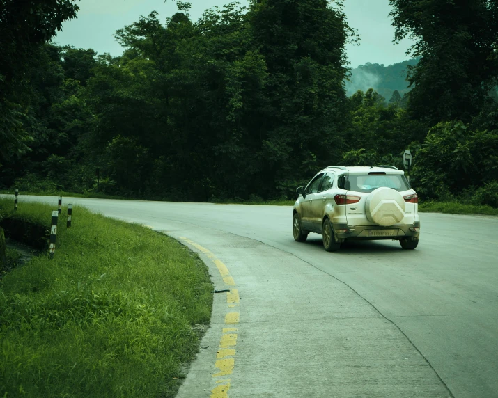 a car driving down a rural road on a cloudy day