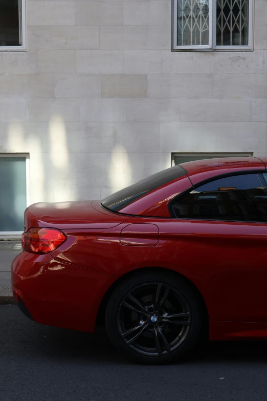 a parked red bmw parked next to a building