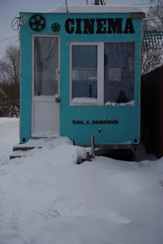 a movie theater sitting in the snow by a house