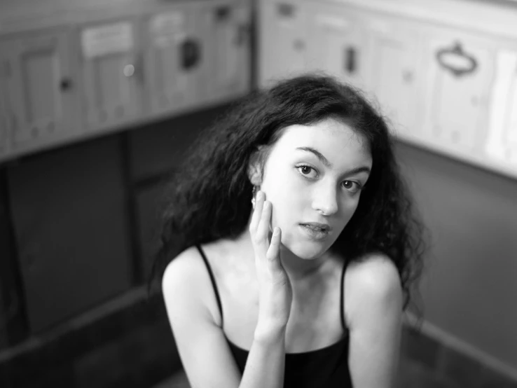 a woman with brown hair and wearing a tank top sitting in a kitchen with the floor in front of her