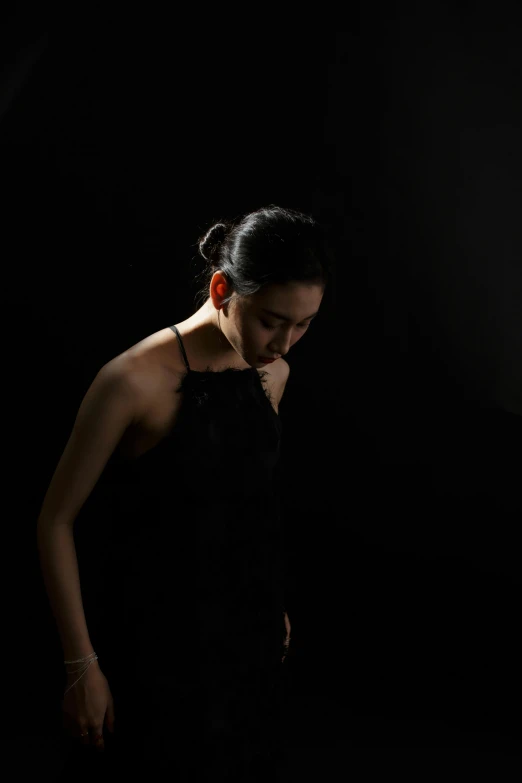 a woman in a black dress standing up against a dark background