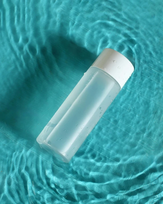 an empty water bottle floating in a pool of water