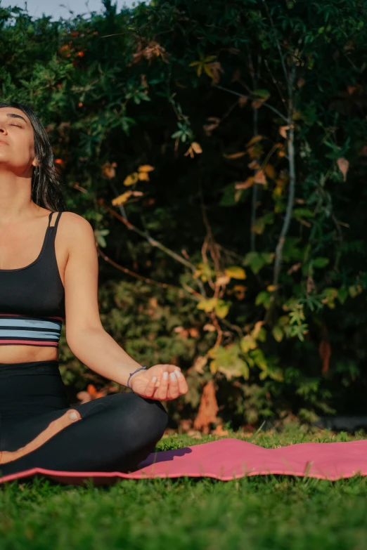 a beautiful woman sitting in yoga gear meditating