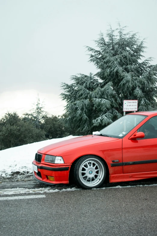 red car with white tires parked at snowy intersection