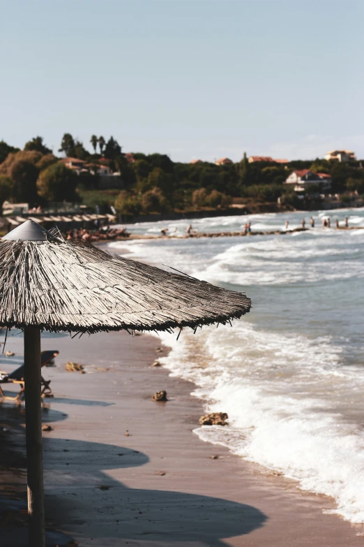 a straw umbrella stands on the shore of the ocean