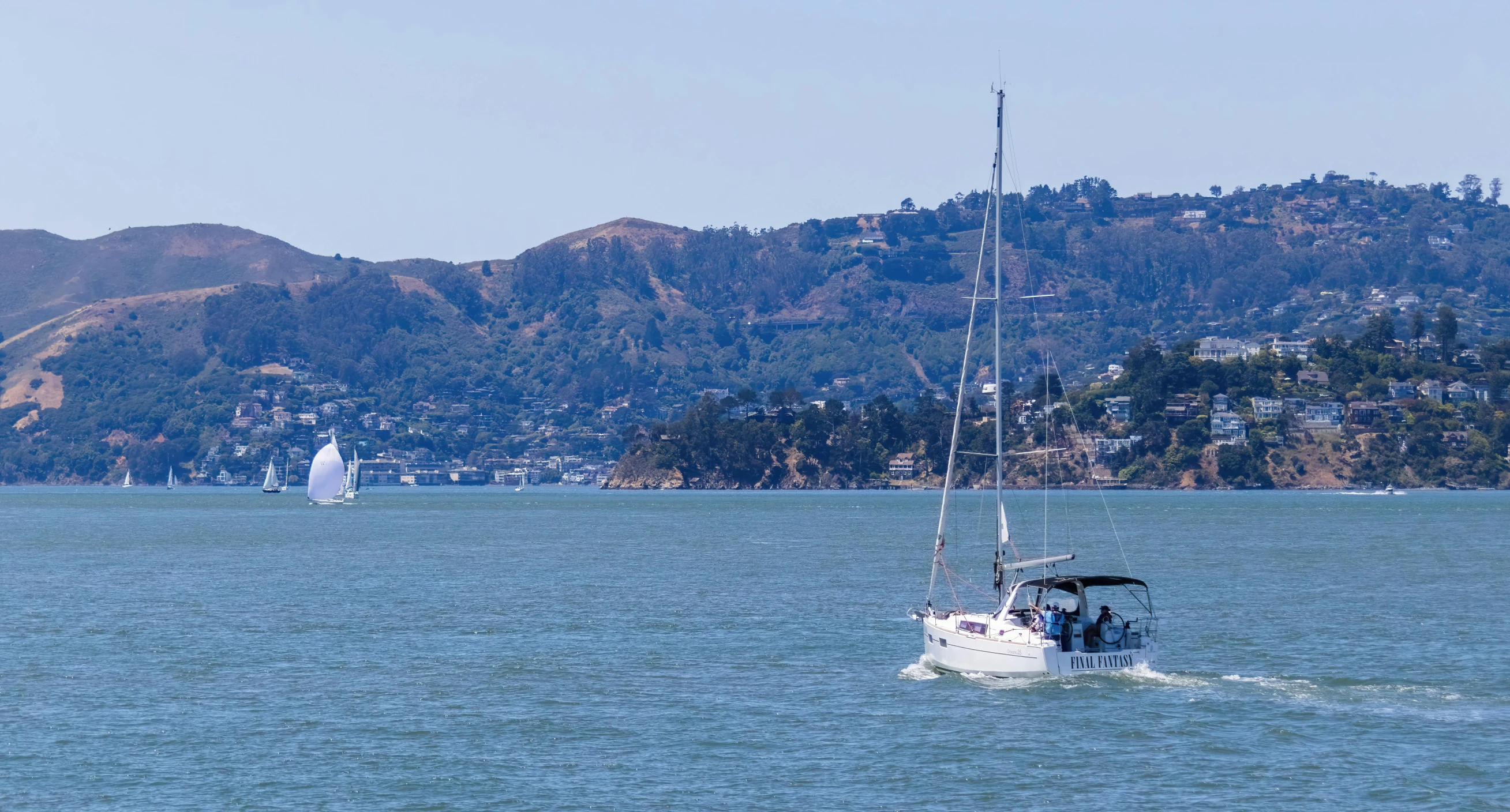 a large boat in the middle of water with a small town on a hill in the distance