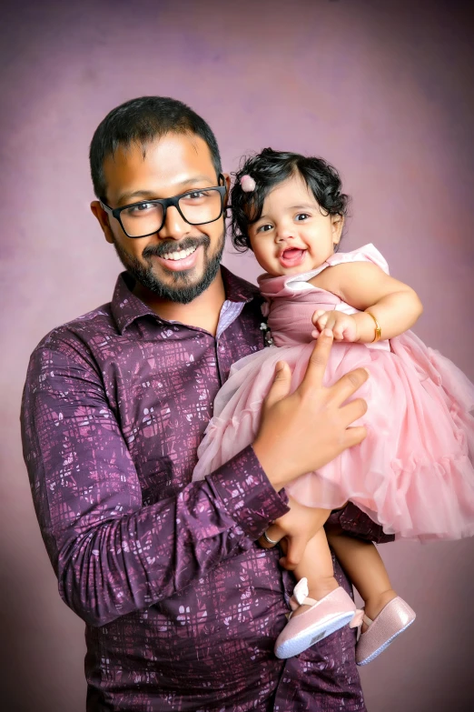 a man holding a little girl while wearing a purple dress