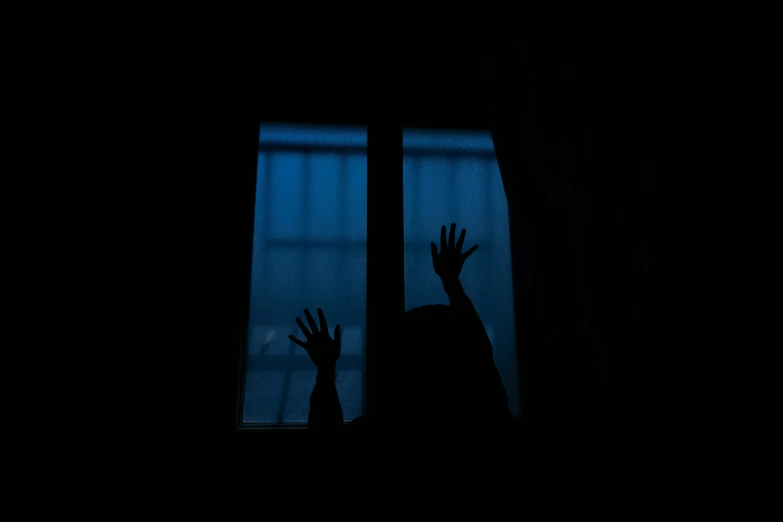 dark silhouette of a person and window at night