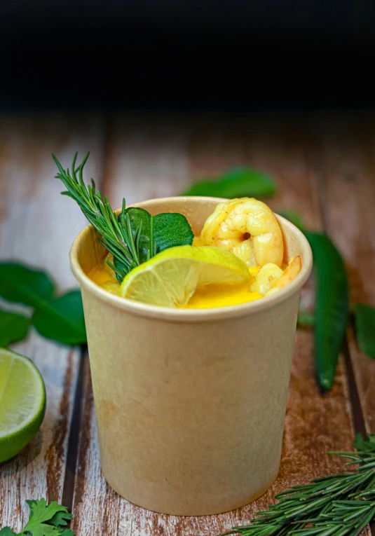 a glass of fresh squeezed water, a lime slice, and some herbs on a wooden table