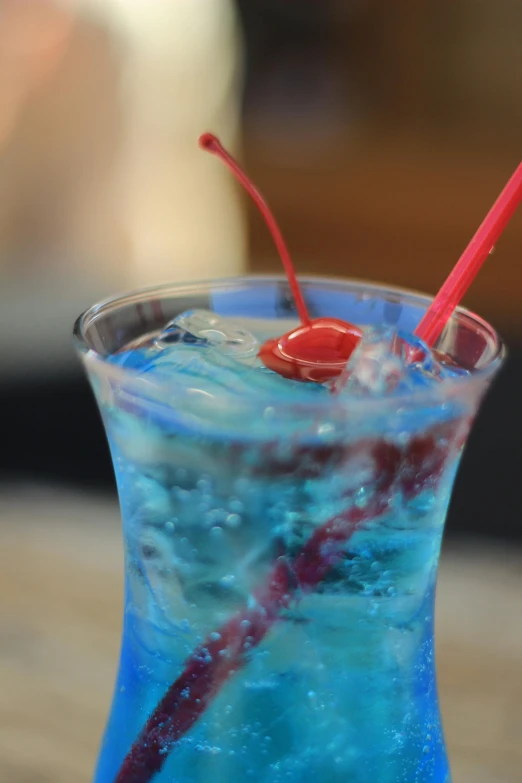 a blue cocktail with red straws in it