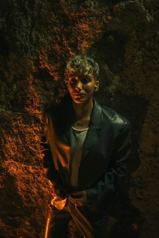 man with jacket leaning against a stone wall