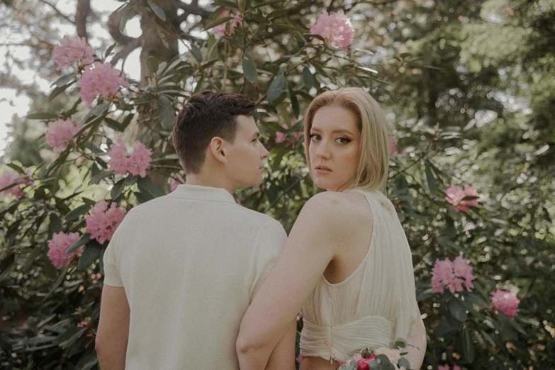 couple standing near flowers in a garden for wedding portraits