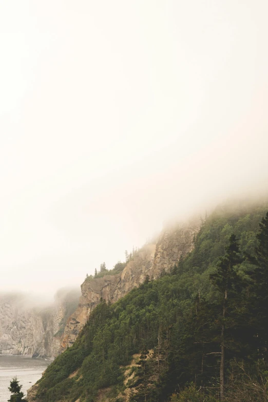 misty mountain side next to body of water