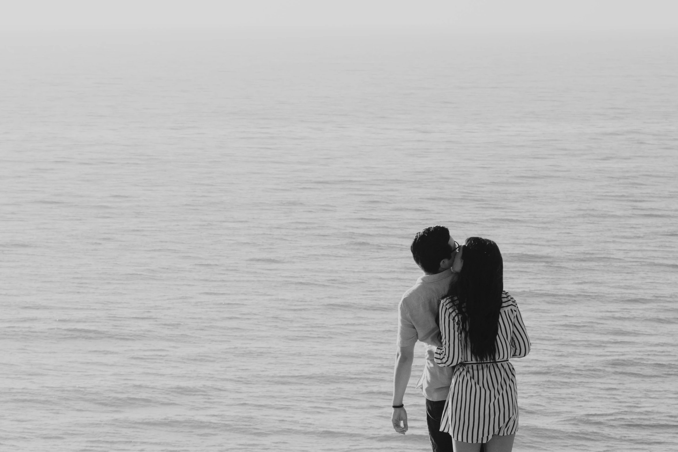 two people standing on the sand near the water