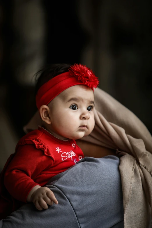 a baby girl laying on the leg of someone else