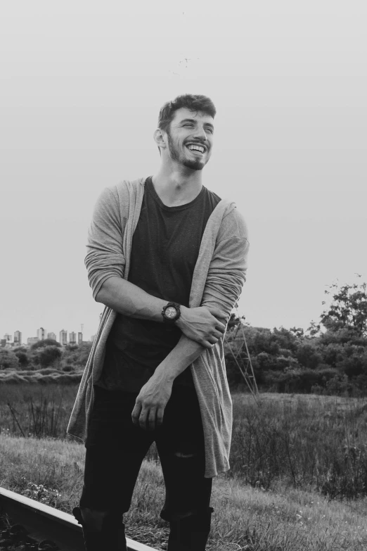 the young man is standing next to a rail in the grass