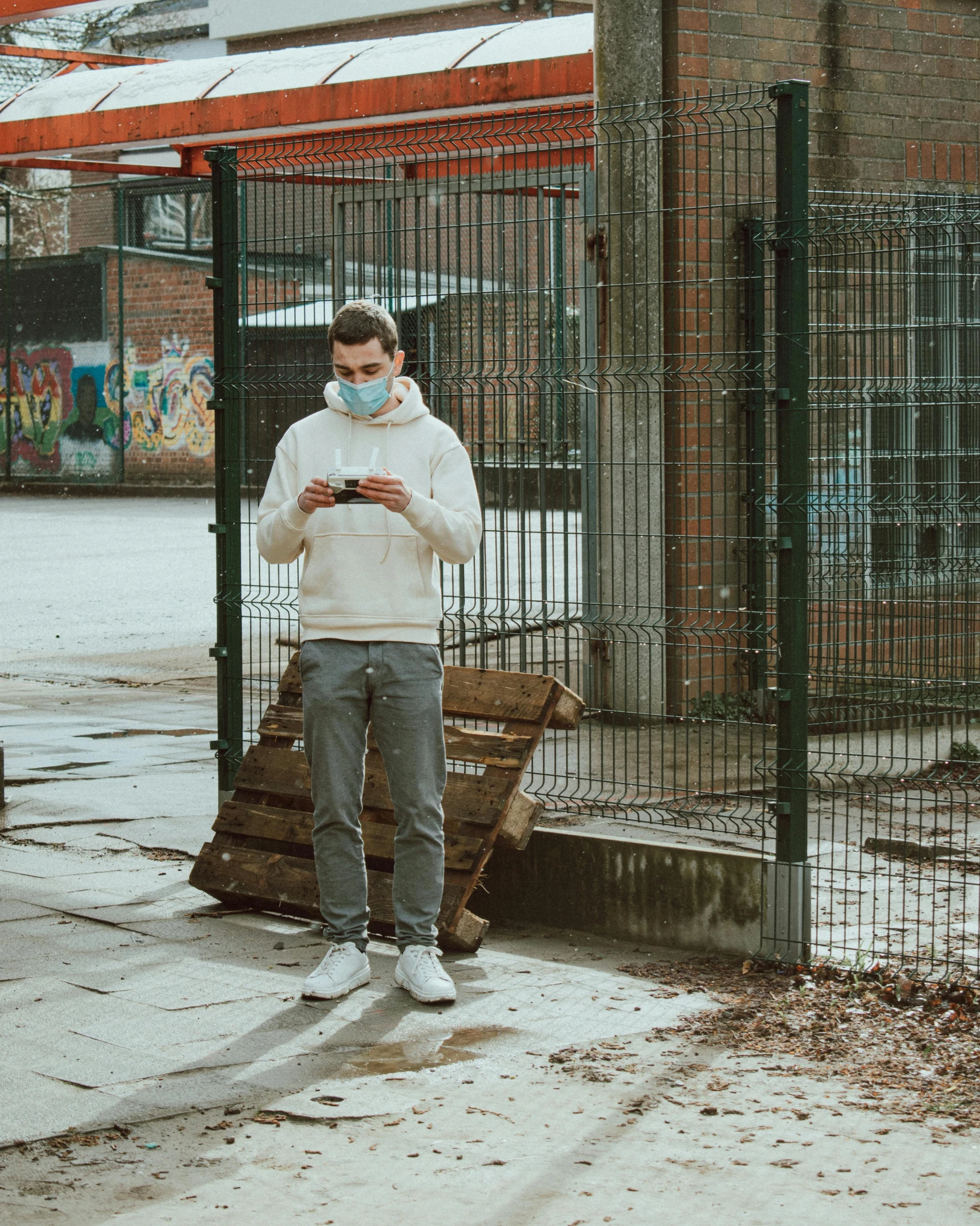 man wearing face mask looking at his cell phone in front of a  cell