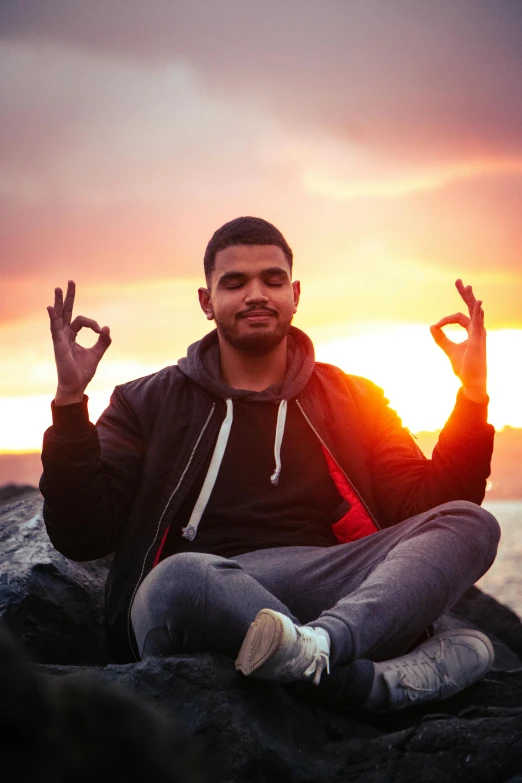 man doing yoga in front of a sunset