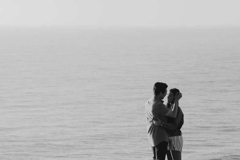 the couple is standing in front of the water