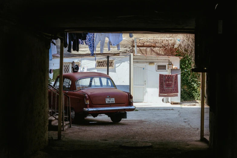 an old classic car parked in an alley between two houses