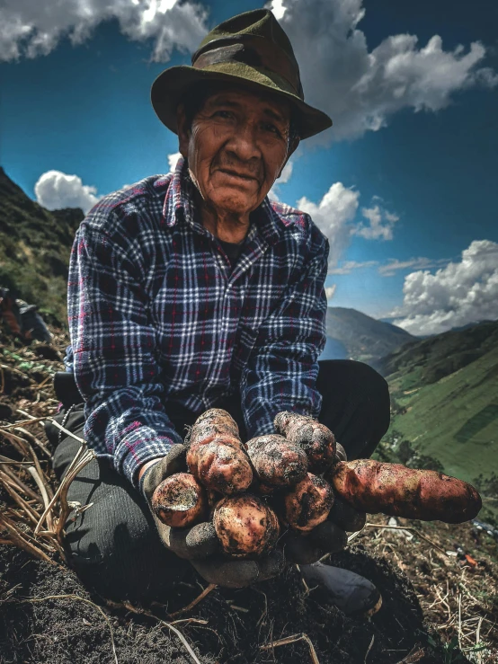 the man is squatting down near many large mushrooms