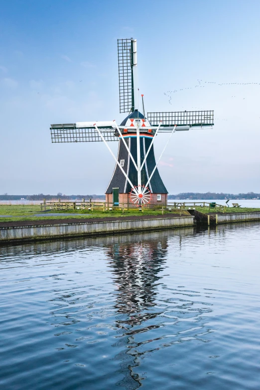 a windmill sits in the water near a building