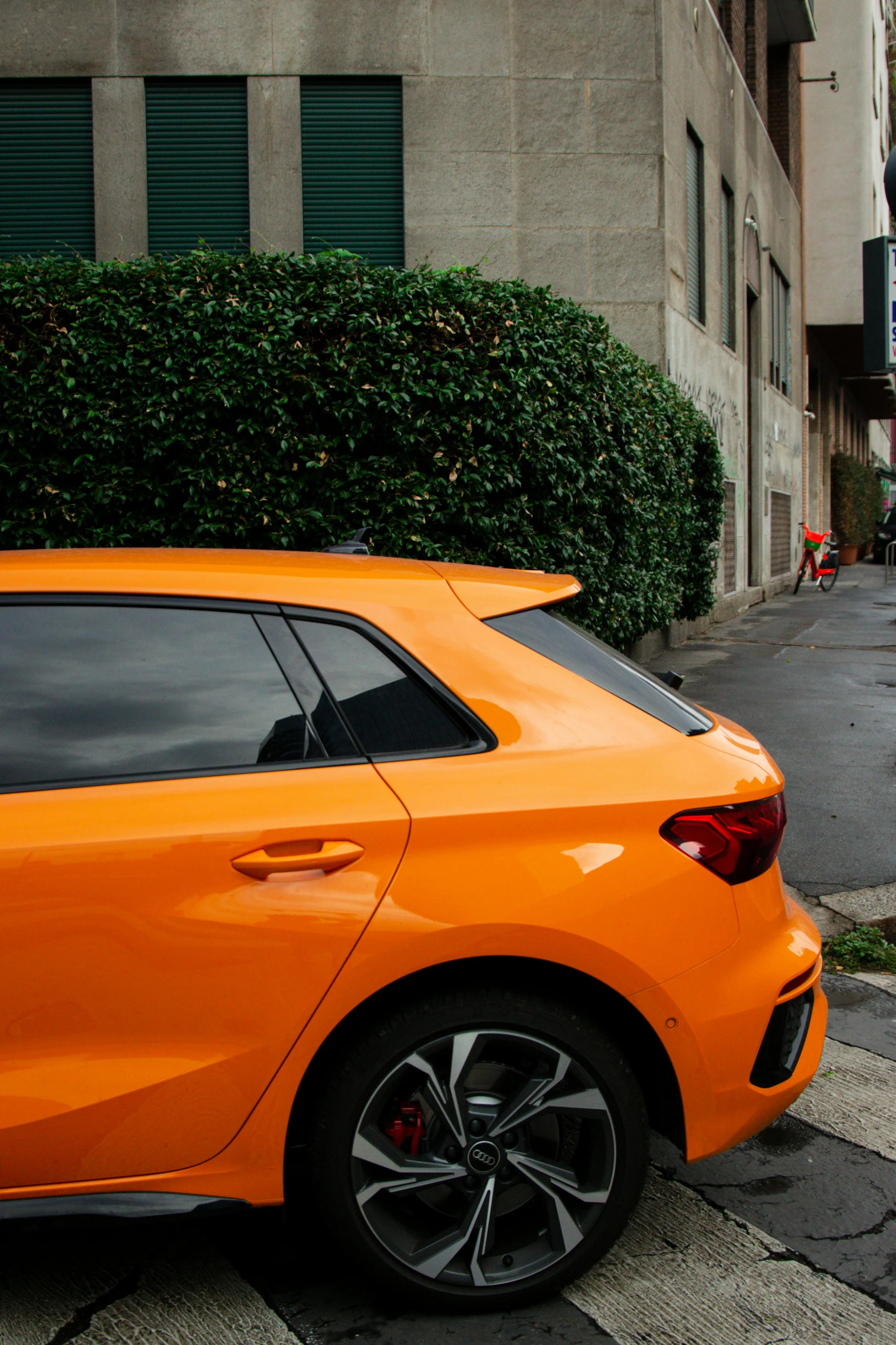 the orange car is parked on the sidewalk