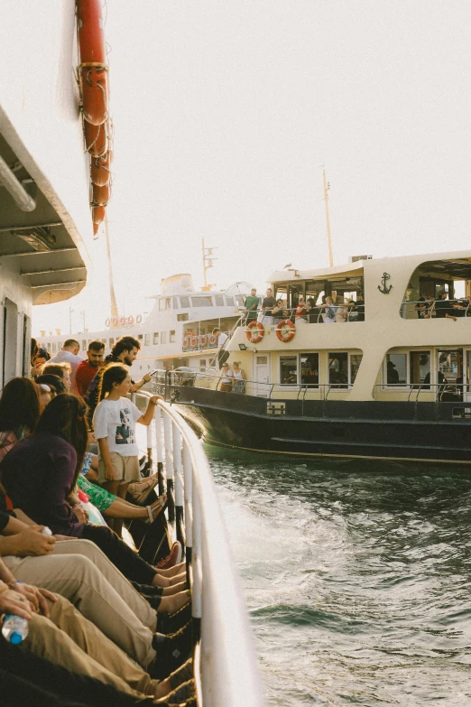 people sitting on the edge of a boat while watching another boat pass by