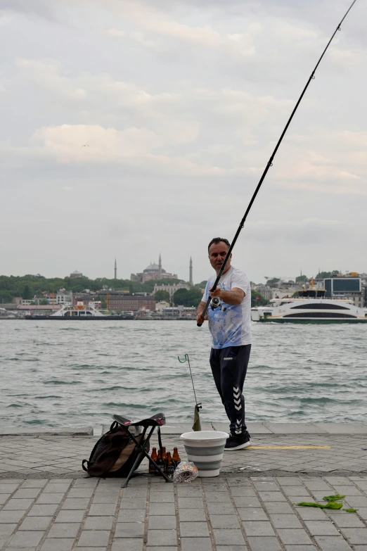 the man is holding a fish and fishing on the waterfront