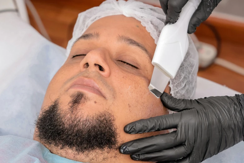 a male wearing a black glove is getting a haircut