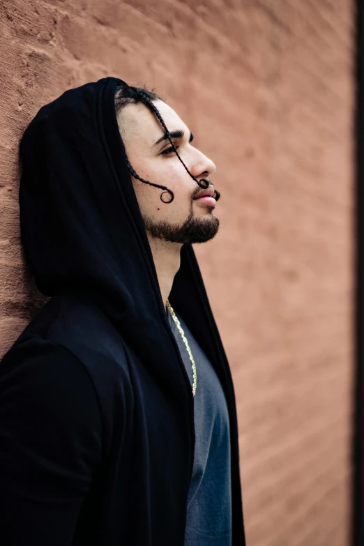 man in hoodie leaning up against a wall