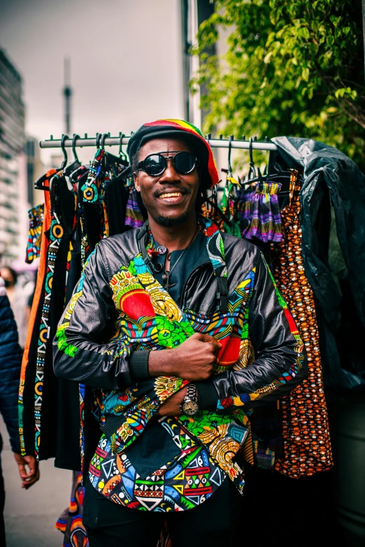 a man with sunglasses standing with clothes on a rack