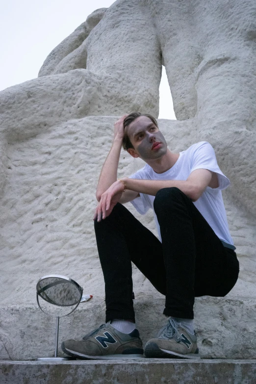 a man sits on the ledge outside with his foot on his head