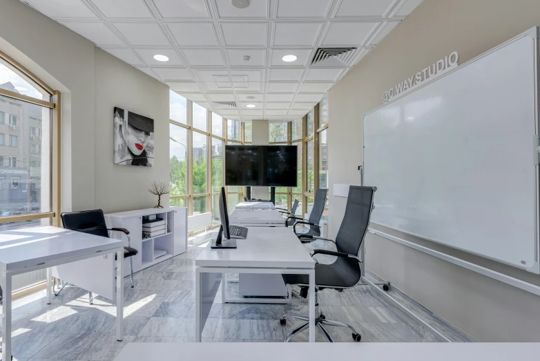 an empty meeting room with desks, chairs and a projection screen