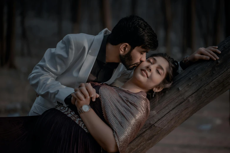 an engaged couple hugging as they lean on a log