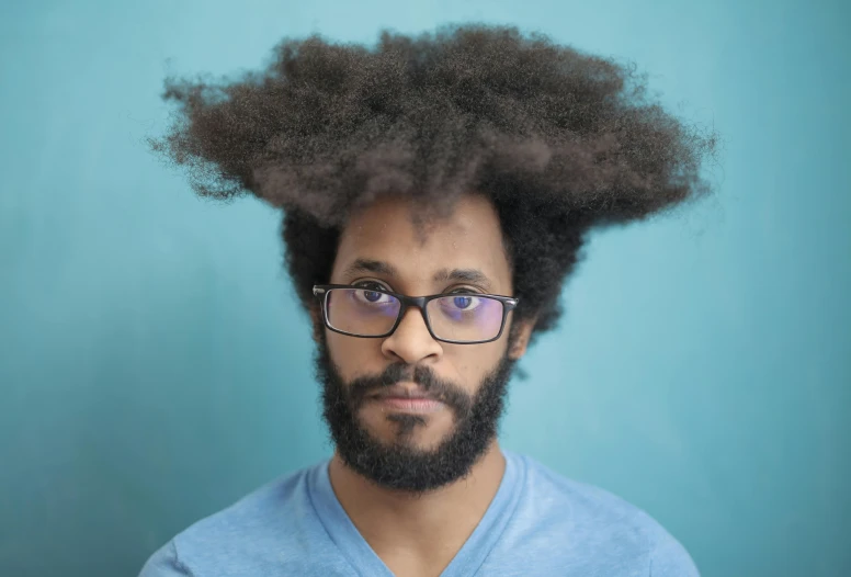 a man with a afro in glasses posing for the camera