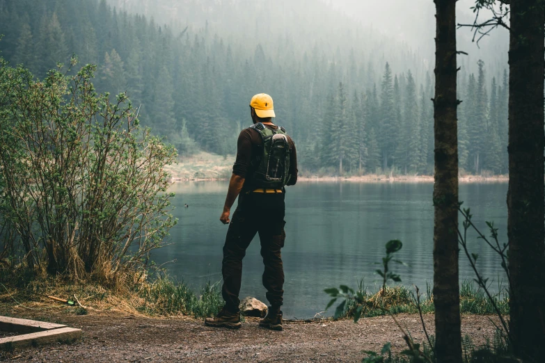 a man is standing by the water with a helmet on