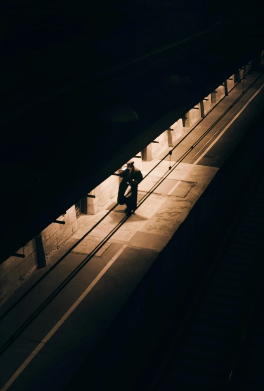 a man sitting on a rail in the middle of a subway station