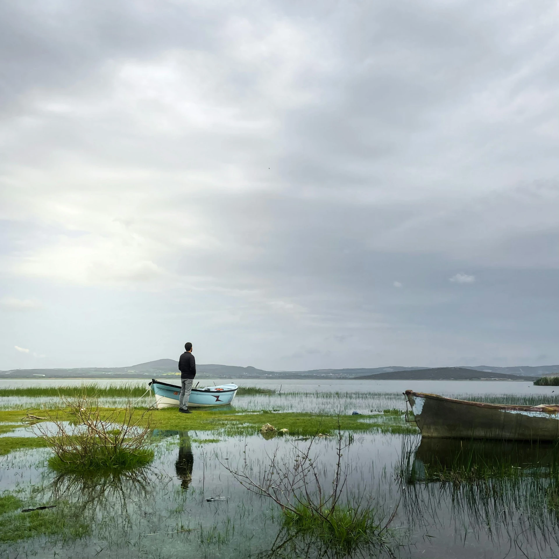 two boats parked on the shore with a man sitting in one