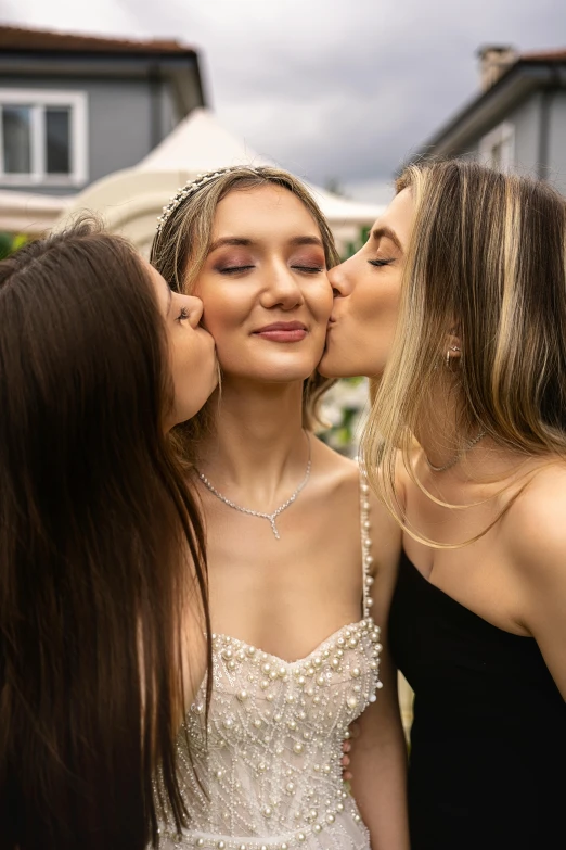 three young women are kissing while dressed in black